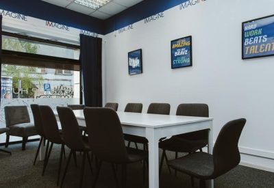 Bright conference room with a white table, dark chairs, and inspirational wall art.
