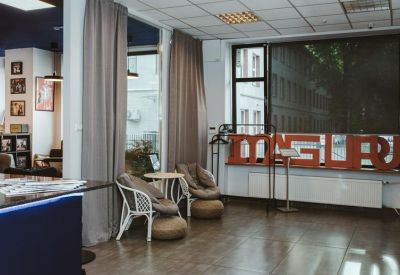 Relaxed communal lounge area with wicker chairs and a large window overlooking trees.