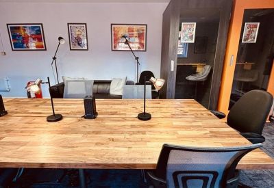Collaborative area with a large oak table, desk lamps, and soundproof phone booths.
