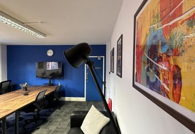 Meeting room with a long wooden table, blue accent wall, and framed abstract art.