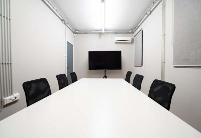 Sleek conference room with a long white table and black mesh chairs.