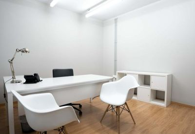 Bright white private office with a large desk and mid-century modern style chairs.
