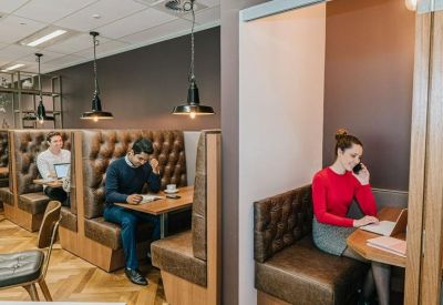 Coworking area with leather booths, wooden floors and warm pendant lighting.