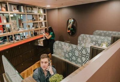 Modern reception desk area with shelving and a man on a phone.