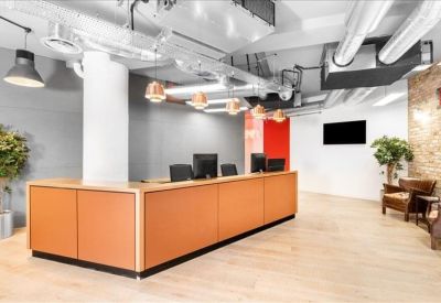 Modern reception area with a long wood-fronted desk and exposed ceiling ductwork.