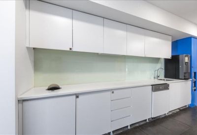 Communal kitchen area with sleek white cabinetry and blue pillar accents.