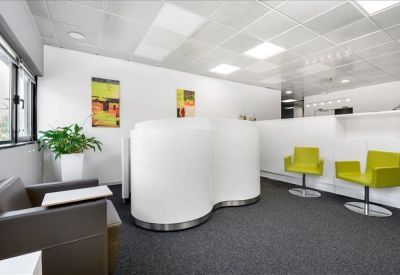 Reception area with a white curved front desk and lime green visitor chairs.