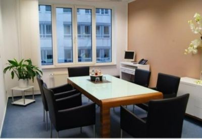 Small meeting room with a wooden table, black chairs, and a large window overlooking the street.