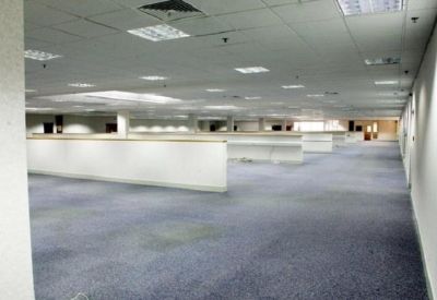 Spacious open-plan office floor with blue carpeting and white partition walls.