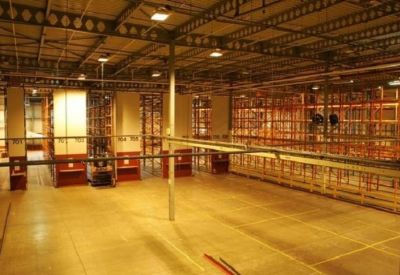 Industrial warehouse interior with high ceilings and extensive metal shelving units.