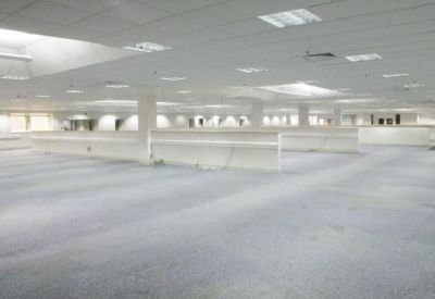 Bright, empty office space with rows of low white partitions under a grid ceiling.