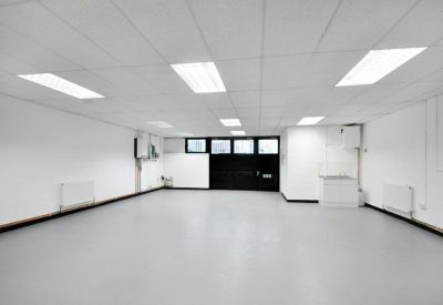Brightly lit white office space with recessed ceiling lights and a small kitchenette area.