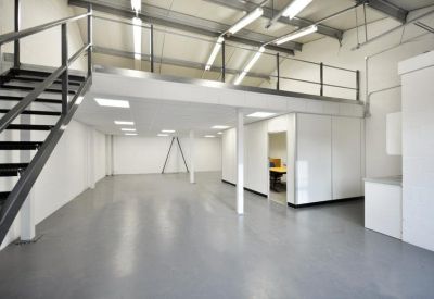 Spacious open-plan industrial unit with a mezzanine level and grey floors.