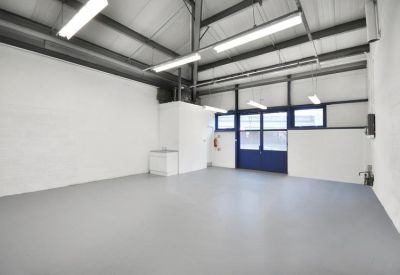 Empty warehouse space with high ceilings and blue double doors.
