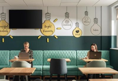 Lounge area with teal quilted seating and lightbulb wall graphics with motivational text.