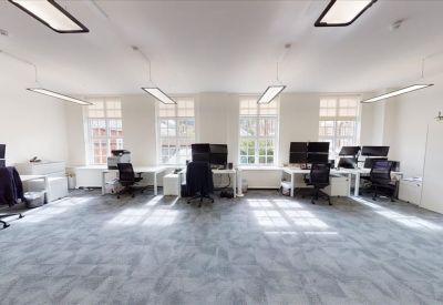 Spacious open-plan workspace at 1-2 Castle Lane with large windows and multiple computer workstations.