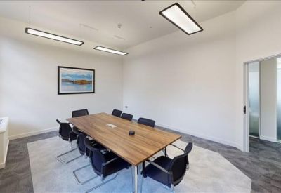 Professional meeting room with a large wooden table, black chairs, and framed artwork.