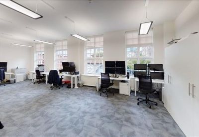 Bright office space featuring white desks, ergonomic chairs, and large windows for natural light.