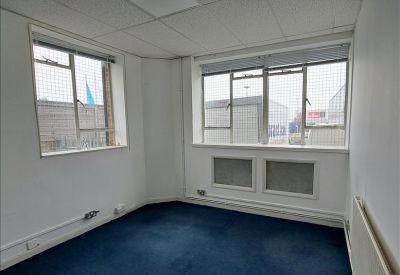 Bright corner office with blue carpeting and multiple windows offering natural light.
