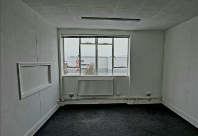 Small private office space with grey carpet, a radiator, and a large window.