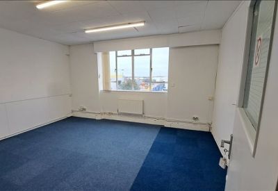 Open office suite with blue carpet tiles and dual overhead tube lighting.