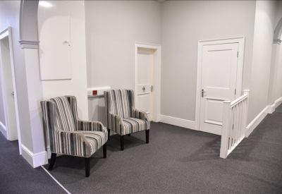 Communal landing area with striped armchairs and grey carpeting.