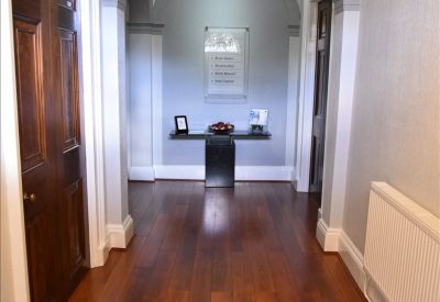 Grand entrance hallway with hardwood floors, white archway, and chandelier.