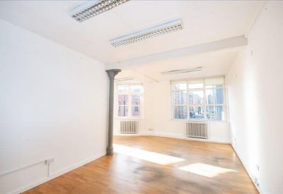 Bright open-plan office space with wood flooring and large windows.