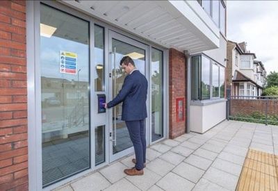 Secure entrance with glass doors and a man using an electronic access keypad.
