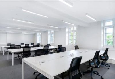 Bright open-plan workspace with white desks and black ergonomic chairs.