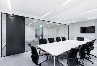Glass-walled meeting room with a large white table and black leather chairs.