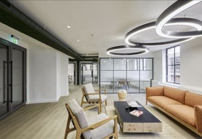 Spacious lounge area with tan sofa, modern armchairs, and circular LED pendant lights.