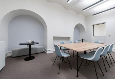 Modern meeting room with a light wood table, blue chairs, and distinctive arched wall alcoves.