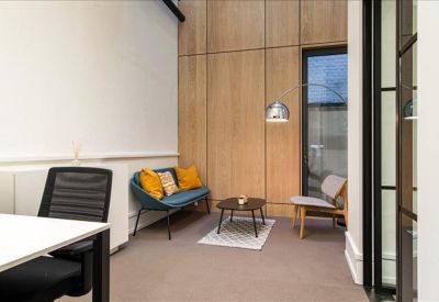 Cozy lounge area with wood-paneled walls, a blue sofa with yellow cushions, and a small coffee table.
