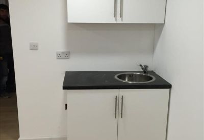 Compact modern kitchenette with white cabinetry and dark countertops.