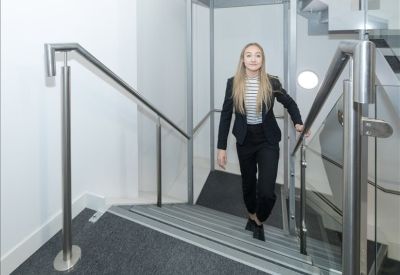 Bright modern staircase with glass balustrades and stainless steel handrails.