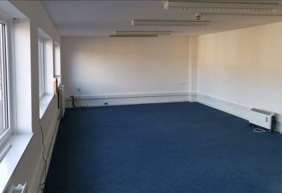 Spacious open-plan office suite with blue carpeting and windows providing natural light.