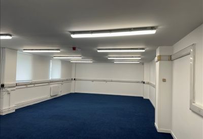 Bright workspace featuring blue carpet and multiple overhead fluorescent lighting fixtures.