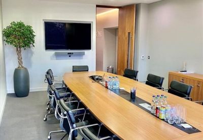 Large boardroom featuring a long wooden table, leather chairs, and a wall-mounted television.
