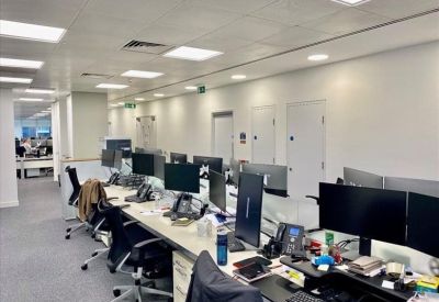 Open-plan workspace featuring rows of modern desks with monitors and ergonomic chairs.