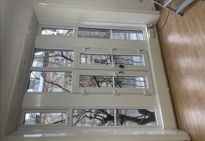 Large white-framed windows with views of the street and local architecture.