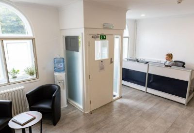 Reception area with a modern white desk, black leather armchair, and water cooler.