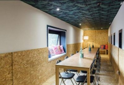 Long communal meeting table in a room with wood-chip walls and a patterned ceiling.