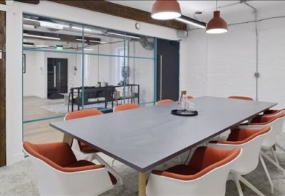 Professional meeting room with a dark grey table, orange-lined chairs, and glass partition walls.