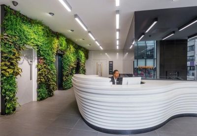 Modern reception area featuring a curved white desk and a vibrant green living wall.