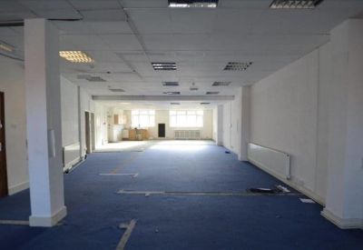 Spacious open-plan office with blue carpeting and white pillars.
