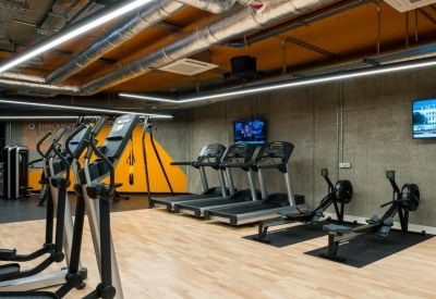 Fitness center featuring treadmills, rowing machines, and warm wood flooring.