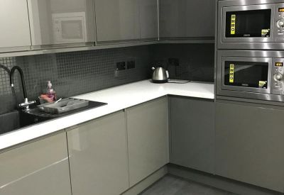 Contemporary kitchen with gloss grey cabinetry, white countertops, and integrated ovens.