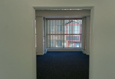 View looking through an open doorway into a carpeted private office with large windows.