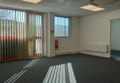 Spacious open-plan office with blue carpeting, fluorescent lighting, and a fire extinguisher.